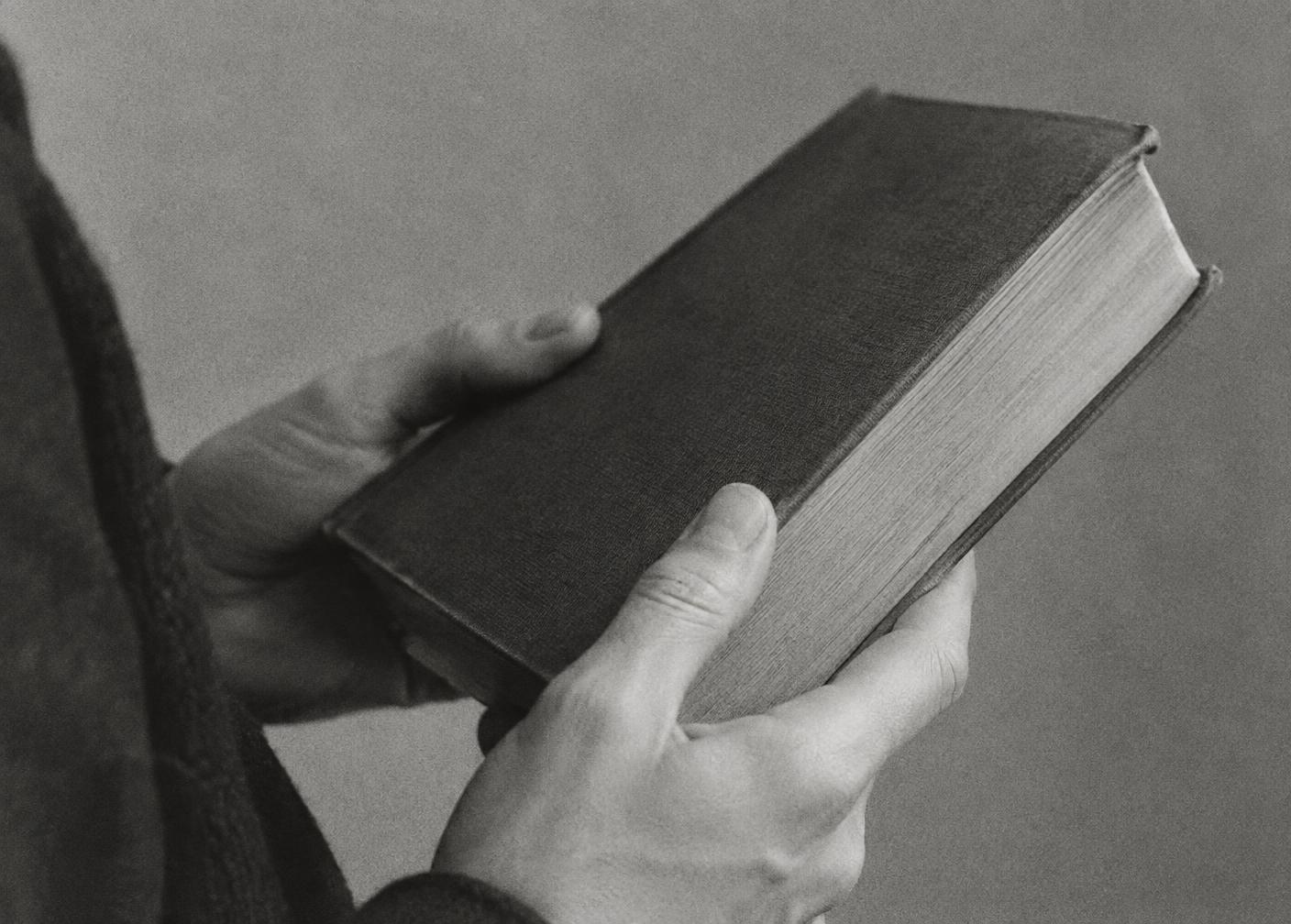 Two hands holding a cloth-bound hardcover memory book